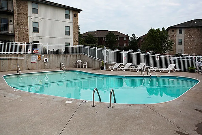Outdoor swimming pool at Lakewood Village Apartments in Springfield, Missouri, surrounded by lounge chairs and secure fencing&mdash;perfect for summer relaxation.