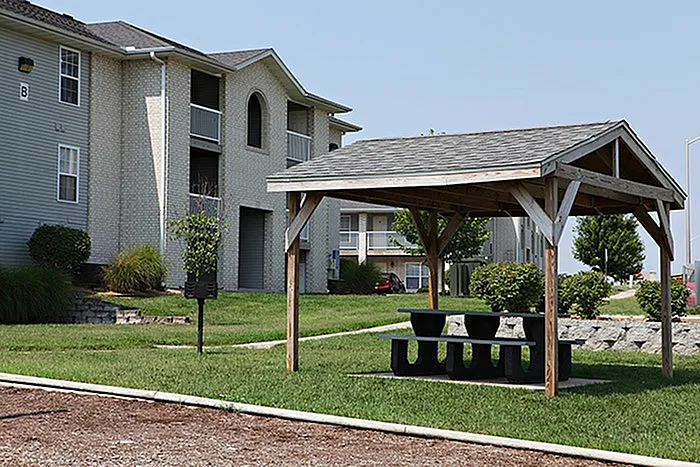 Covered picnic pavilion with bench seating and nearby grill at Lakewood Village, offering residents a shaded space to enjoy outdoor meals and gatherings.