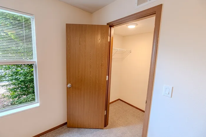 Walk-in closet in the bedroom at Huntley Ridge East, featuring overhead lighting and a built-in wire shelf, perfect for storage and organization.