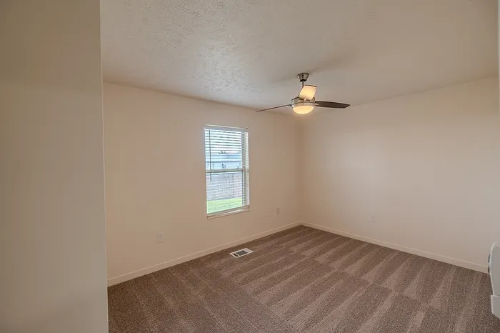 Light-filled bedroom featuring plush carpeting, a window with blinds, and a ceiling fan with light fixture.