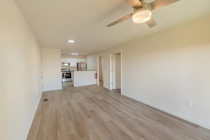 Spacious living room with luxury vinyl plank flooring, ceiling fan, and large windows offering natural light in this 1-bedroom Battlefield apartment.