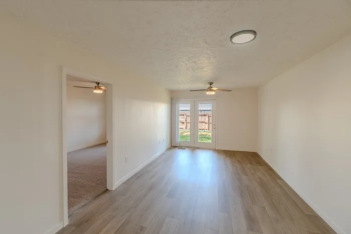Living and bedroom space with two ceiling fans and double glass doors leading to a private backyard&mdash;part of a 1-bedroom apartment in Battlefield.