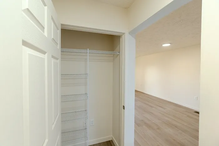 Small hallway linen or coat closet with built-in shelving, conveniently located just off the living area.