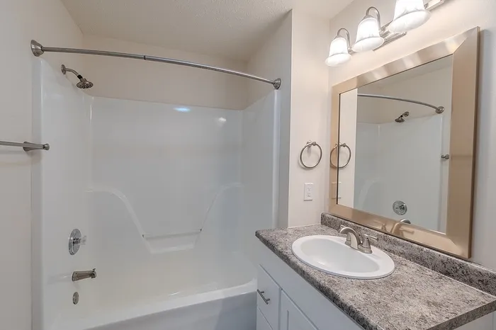 Another view of the bathroom vanity, highlighting the brushed metal framed mirror and ample counter space&mdash;part of a renovated 1-bedroom Battlefield, MO rental.