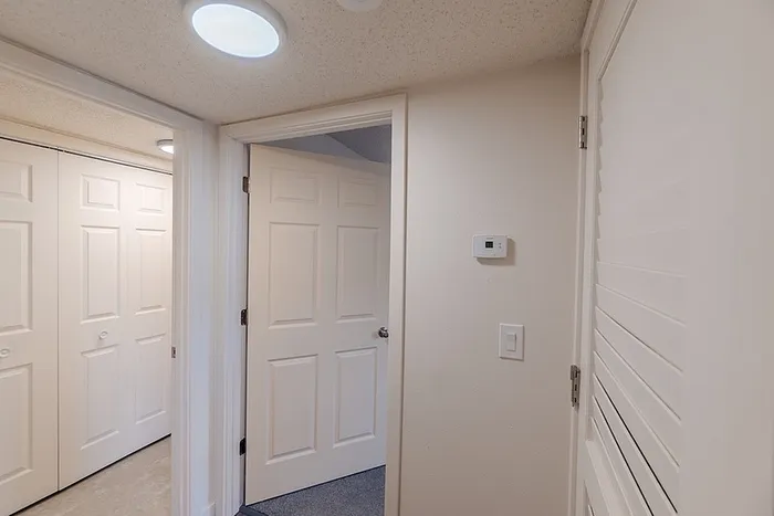 Interior hallway at Huntley Ridge East apartments in Springfield, MO, featuring multiple doors for storage, closets, and bedroom access with neutral wall finishes.