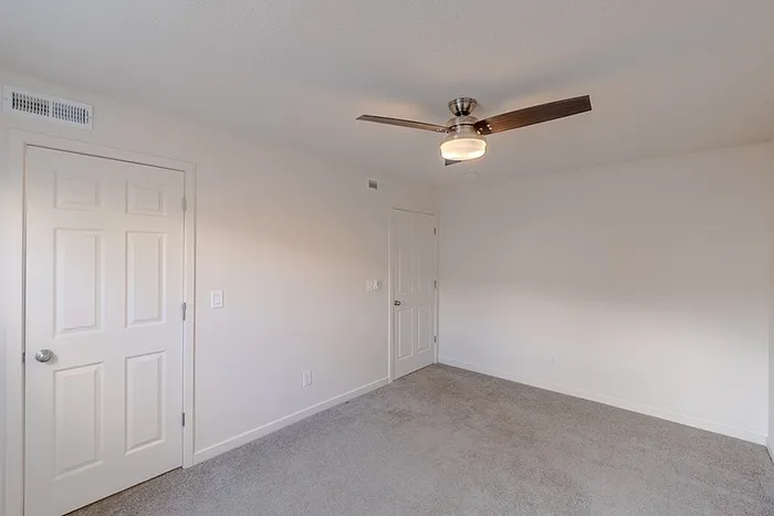 Comfortable bedroom at Huntley Ridge East in Springfield, MO, with carpeted floors, ceiling fan, and double-door closet.