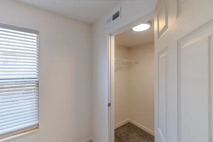 Walk-in closet at Huntley Ridge East apartments, offering built-in shelving and carpet flooring for extra storage space.