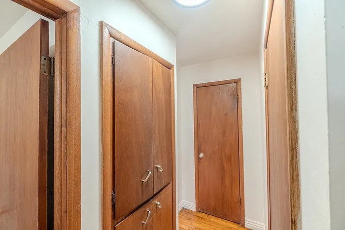Hallway at Village Club Apartments in Springfield, MO, showcasing warm wood doors and built-in storage cabinets.