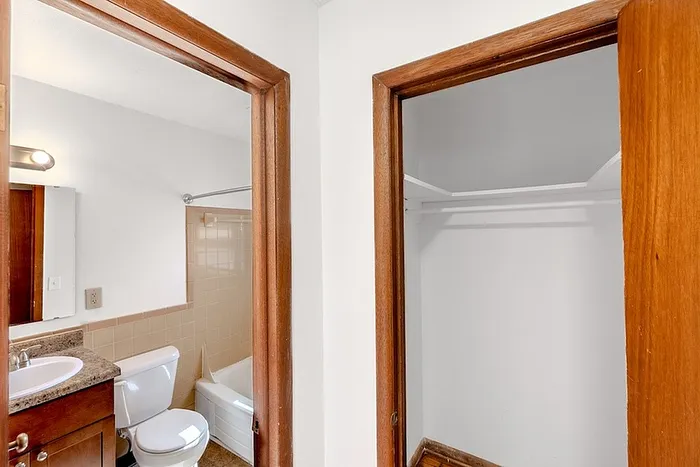 Hallway view leading to a bathroom and closet at Village Club Apartments in Springfield, MO, with natural wood trim and doors.