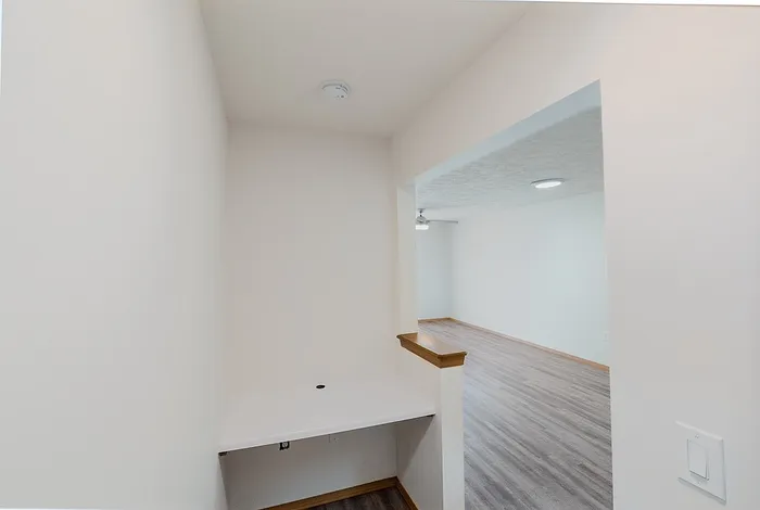 Inviting apartment with a cozy workspace area leading to a spacious, open-plan living room featuring stylish wood flooring.