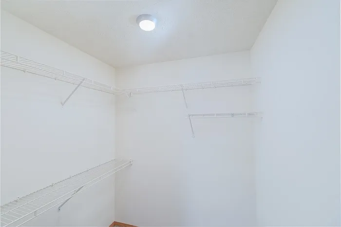 Spacious walk-in closet with ample shelving and bright lighting, perfect for organized storage and easy access.