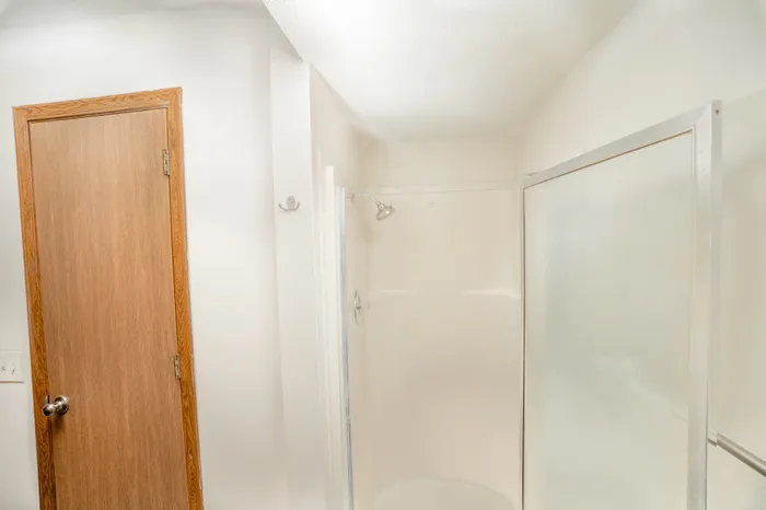 Bathroom shower area at Catalpa East Apartments in Springfield, MO, with a walk-in shower, sliding glass door, and neutral wall finishes.