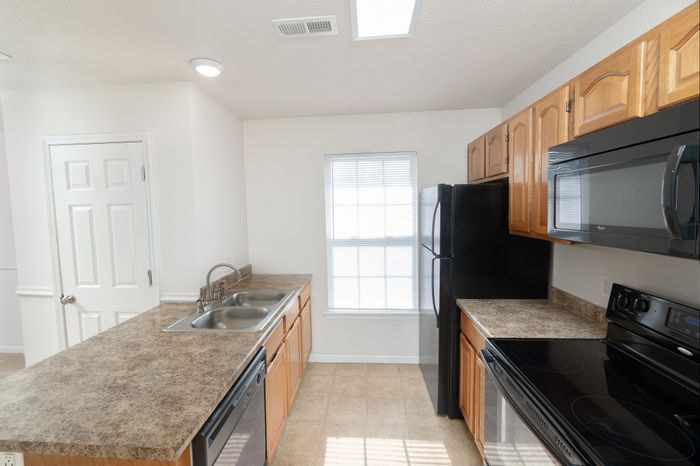 Bright kitchen with sleek countertops, modern appliances, and ample natural light, perfect for culinary creations.
