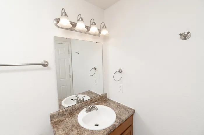Elegant bathroom with sleek vanity, granite countertop, and polished chrome fixtures under soft, ambient lighting.