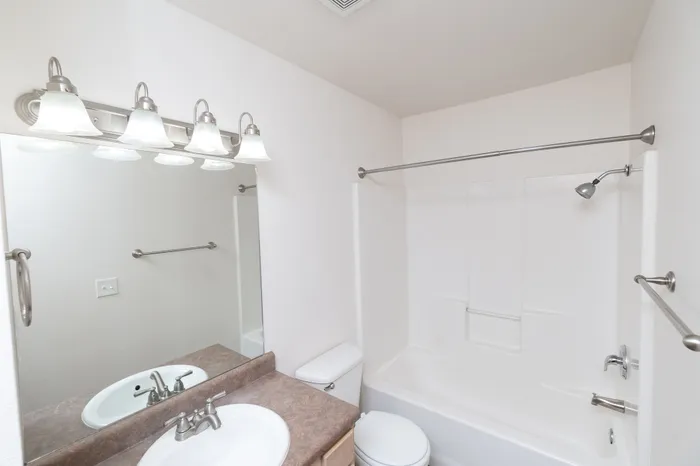 Bright and modern bathroom with a sleek vanity, large mirror, and elegant lighting fixtures.