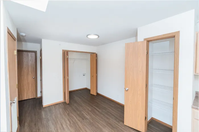 Bright, spacious room featuring sleek hardwood floors, open closet space, and modern shelving for stylish organization.