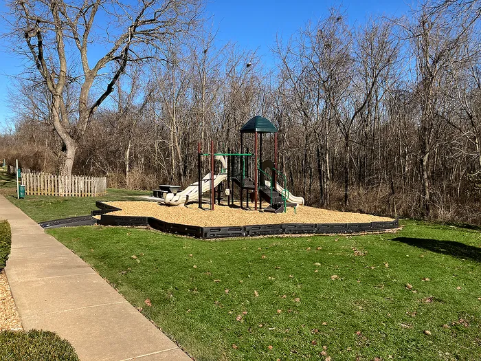 Charming outdoor playground surrounded by lush greenery, featuring slides and a climbing area, ideal for family fun.