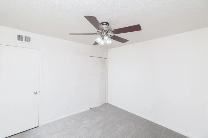 Unfurnished bedroom at Seminole North Apartments with white walls, carpeted flooring, ceiling fan with light fixture, and a single-door closet.