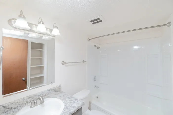 Bright and airy bathroom with elegant lighting, spacious vanity, and modern fixtures.