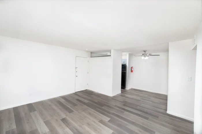 Bright and modern open-concept living space with wood-style flooring and ceiling fan, perfect for relaxing and entertaining.