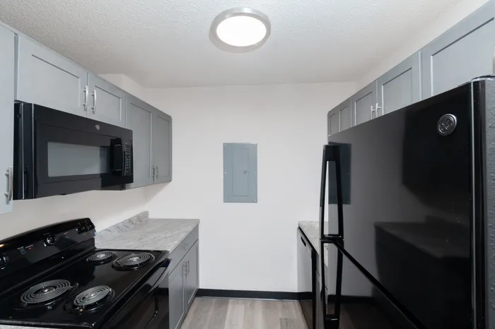 Modern kitchen with sleek black appliances, elegant gray cabinets, and pristine marble countertops.