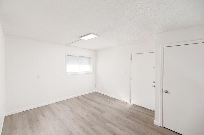 Bright and inviting apartment entryway featuring sleek hardwood floors and modern white walls, perfect for a minimalist aesthetic.