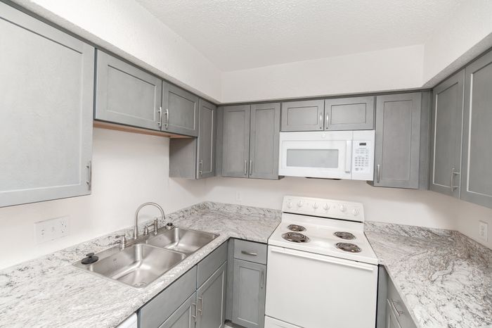 Modern kitchen with elegant gray cabinetry, sleek granite countertops, and a built-in microwave for convenient living.