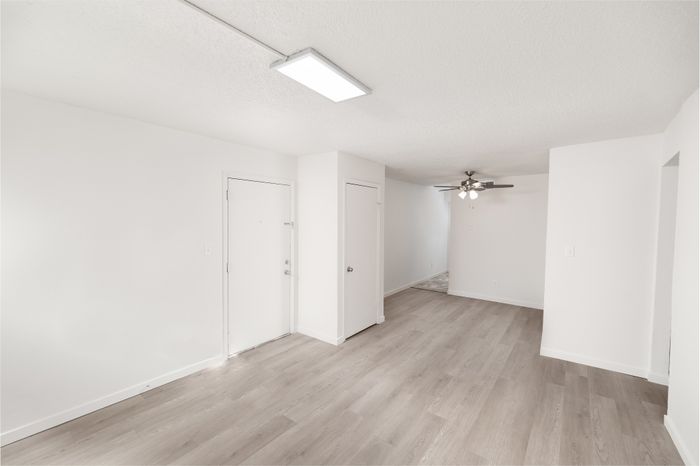 Bright and inviting apartment interior with modern wood flooring, recessed lighting, and a stylish ceiling fan.