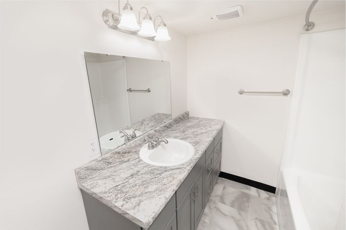 Modern bathroom with elegant marble countertop, sleek fixtures, and soft overhead lighting.