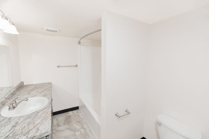 Bright and modern bathroom featuring a sleek marble countertop, elegant fixtures, and a classic bathtub, offering a serene and stylish retreat.
