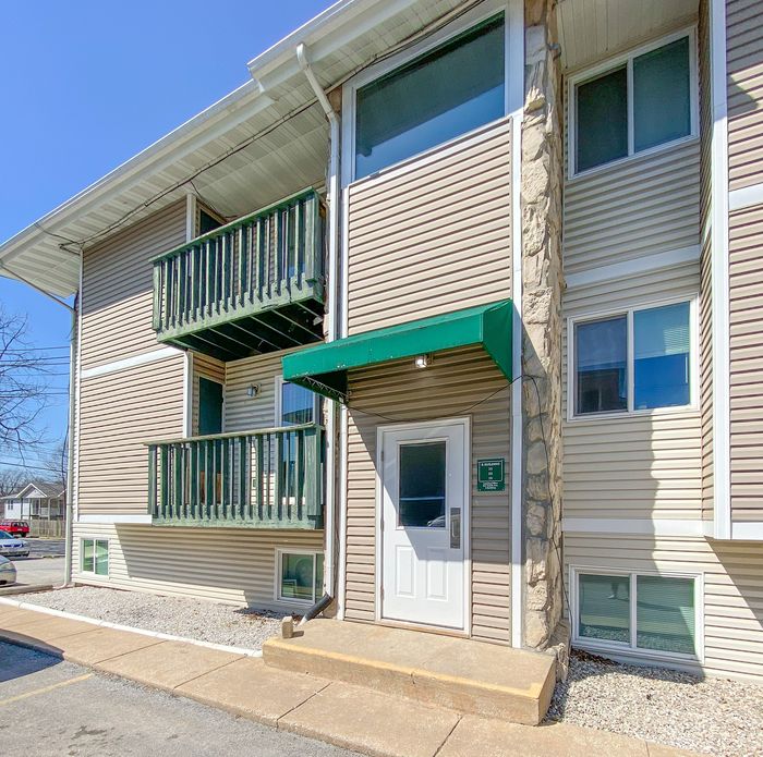 Charming apartment exterior featuring modern siding, cozy balconies, and a welcoming entry under a green awning.