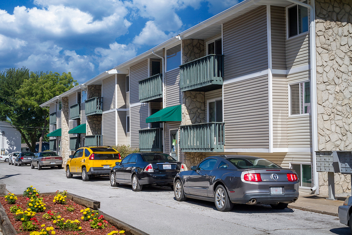 Charming apartment complex with stylish balconies, vibrant landscaping, and convenient parking under a clear blue sky.
