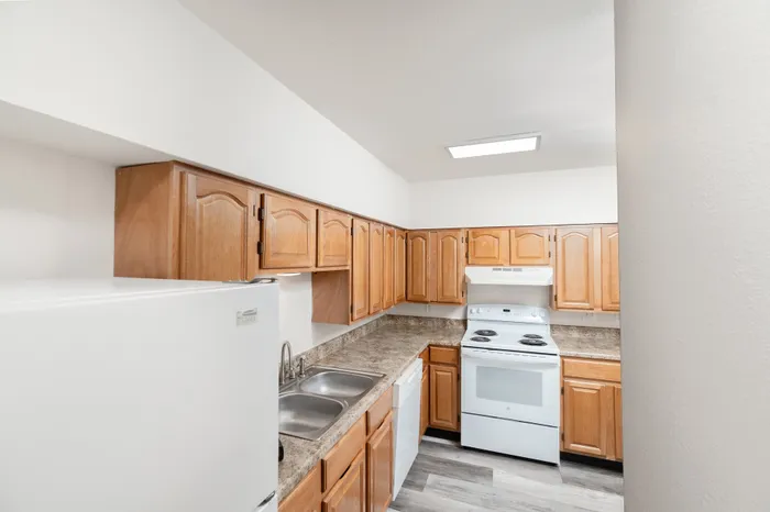Kitchen with wood cabinets, laminate countertops, refrigerator, dishwasher, and electric range at Lombard Heights Apartments.
