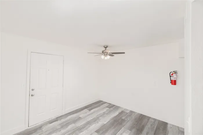 Dining area with front door entry, ceiling fan, and vinyl plank flooring at Lombard Heights Apartments.