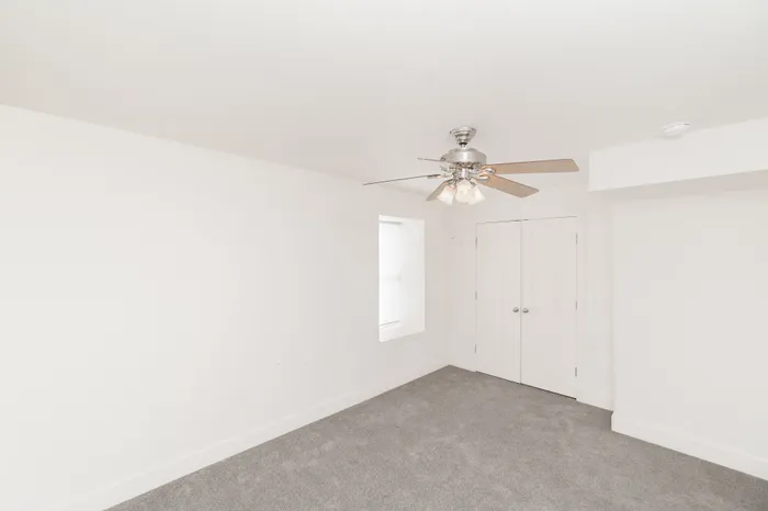 Bedroom with carpet flooring, ceiling fan with light, and double-door closet at Lombard Heights Apartments.