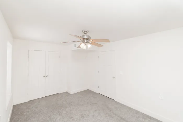 Bedroom with carpet flooring, ceiling fan with light, and double-door closet at Lombard Heights Apartments.
