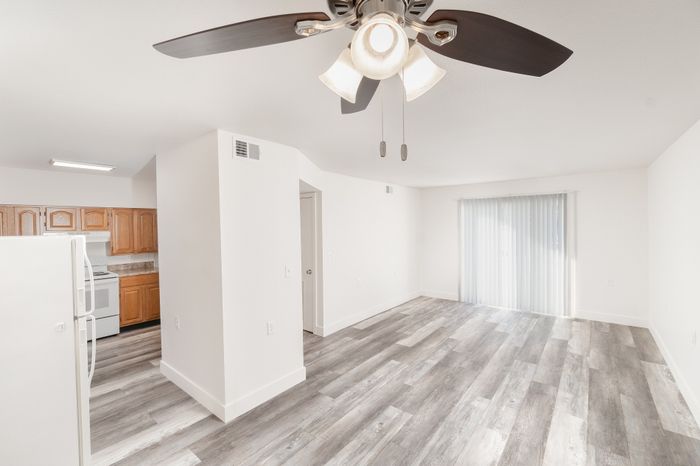 Open living area with vinyl plank flooring, ceiling fan, and kitchen entry at Lombard Heights Apartments.