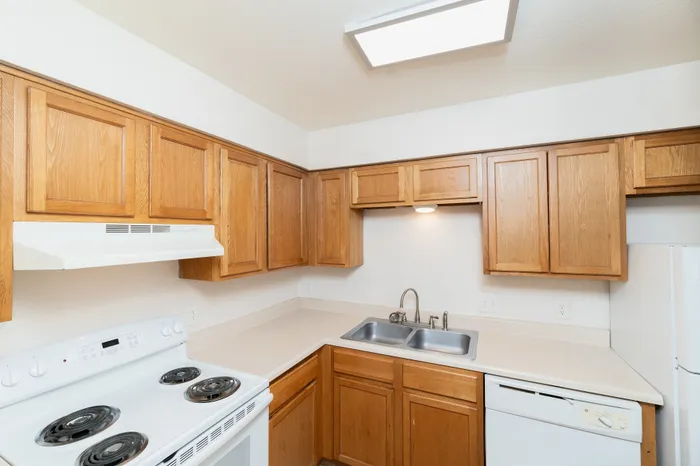 Charming kitchen with warm wooden cabinetry, sleek countertops, modern stove, and built-in sink under bright lighting.