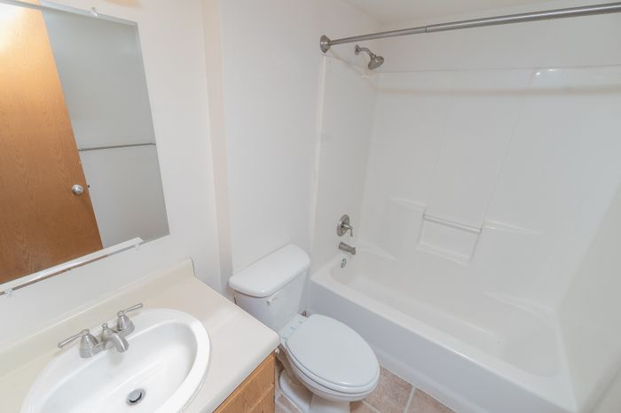 Bright and modern bathroom with a sleek white bathtub, elegant sink, and polished fixtures.