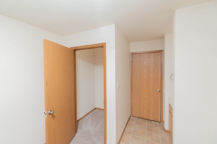 Bright and inviting corridor featuring elegant wood doors and neutral tile flooring, perfect for a cozy apartment setting.