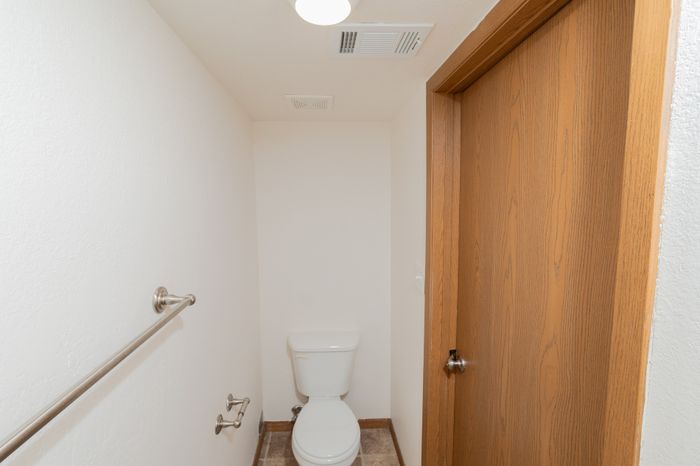 Bright and clean compact bathroom showcasing a sleek, modern toilet and elegant wooden door.