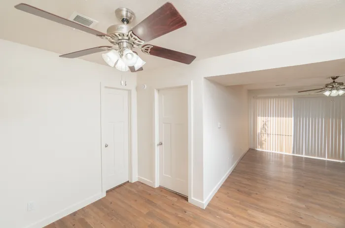 Living area with ceiling fan, wood-style flooring, interior doors, and open layout leading to patio.