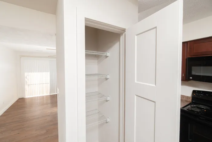 Pantry with white wire shelving and door, located in the kitchen area.