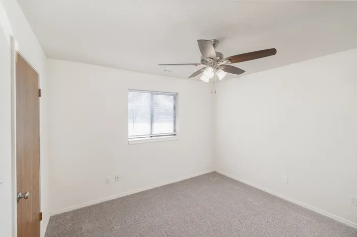 Bedroom with ceiling fan, neutral carpet, window with blinds and ample wall space