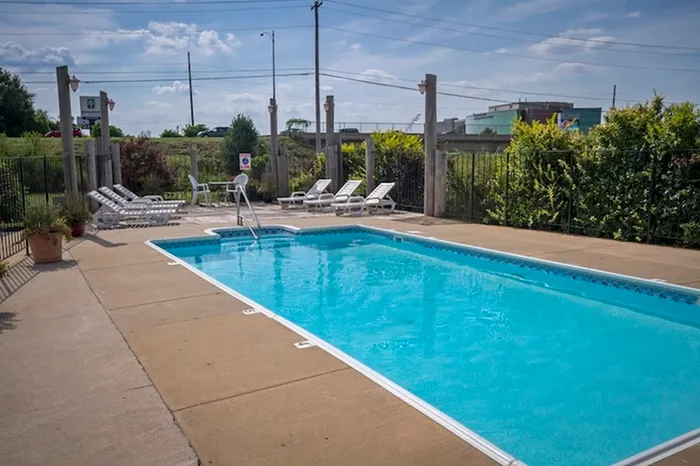 Inviting outdoor pool area with crystal-clear water, surrounded by cozy lounge chairs and lush greenery, offering a perfect spot for relaxation and leisure.