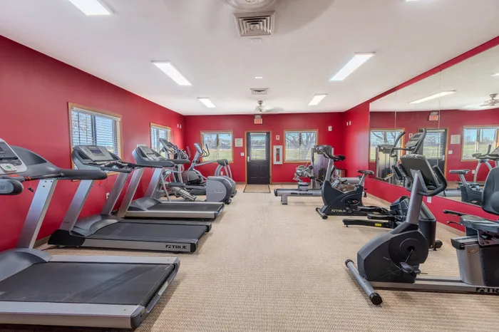 Modern fitness center with vibrant red walls, featuring treadmills and exercise bikes, perfect for active living.