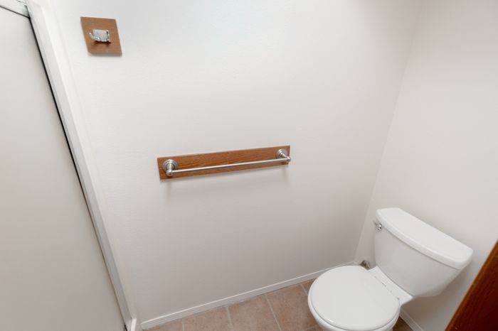 Bathroom toilet area with tile flooring, towel bar, walk in shower and neutral walls.