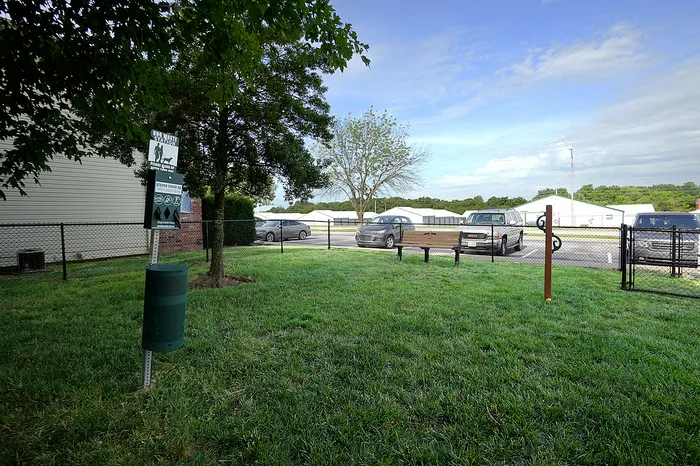 Charming and pet-friendly outdoor space with lush greenery, bench seating, and convenient pet waste station, ideal for relaxation and leisure.