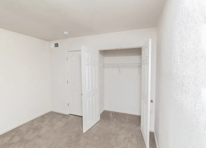 Hillcrest 90 bedroom closet with double doors and built-in hanging shelf for organized storage.