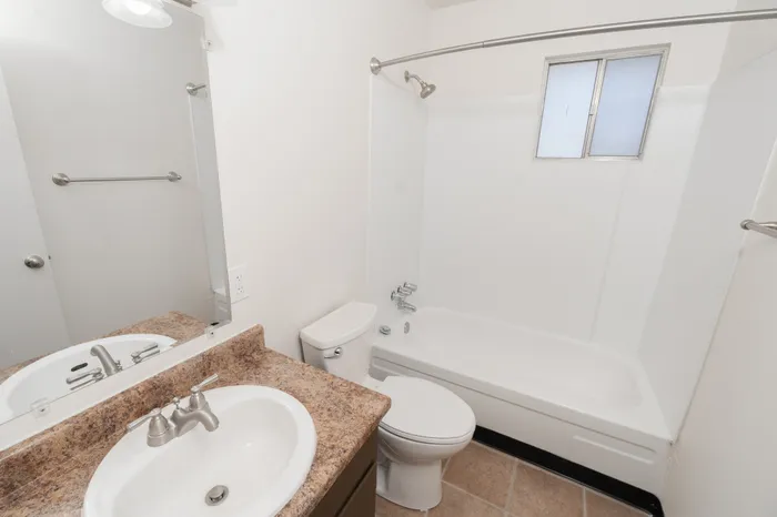 Full bathroom with bathtub and shower, toilet, vanity sink with countertop, and wall mirror with lighting